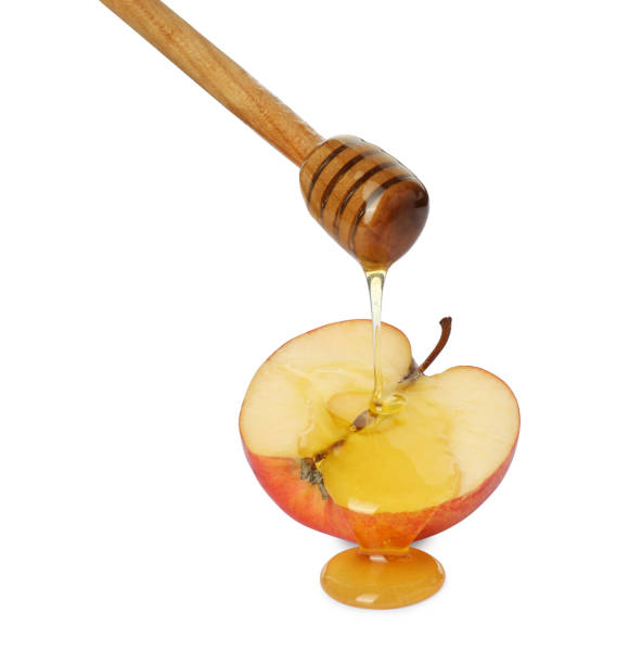 istock Pouring tasty honey onto cut apple on white background 1950324710