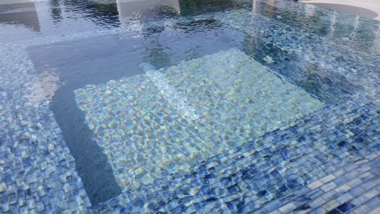 Outdoors hot tub with clear and calm water. Pool constructed with various shades of blue tiles that creating aesthetic. Serene ambiance suitable for relaxation