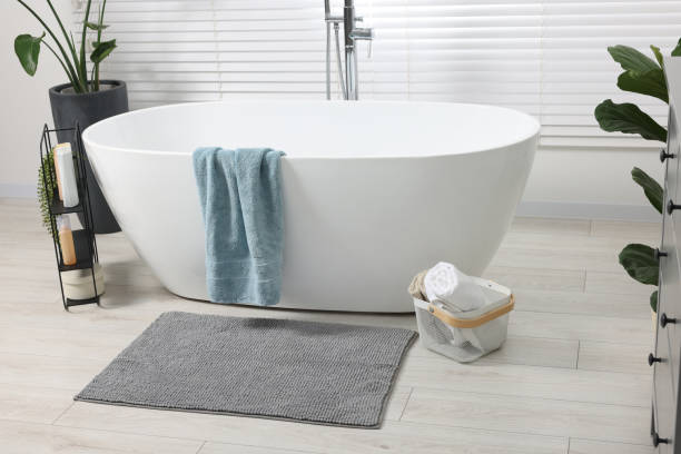 istock Stylish bathroom interior with bath tub, houseplants and soft light grey mat 1950390698