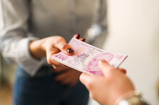 Close-up of handing a stack of Turkish lira to the other person.