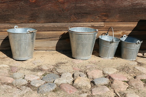 Four tin buckets standing against a wooden wall.