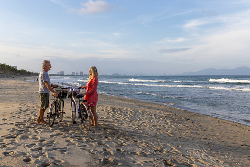 Mature couple relax on beach with bicycles