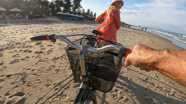 Personal perspective of couple pushing bicycles down beach Personal perspective of couple pushing bicycles down beach together vietnamese old man portrait stock pictures, royalty-free photos & images