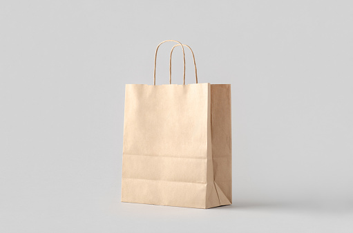 Kraft paper bag with handles, blank mockup isolated on a grey background.