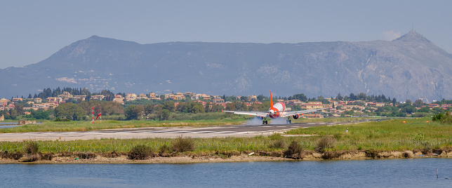 Corfu, Greece - May 10 2022: The passenger plane lands at Corfu Airport. Greece, Corfu Island. Runway against the backdrop of mountains, close-up.