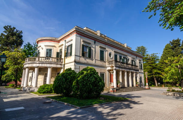 Mon Repos palace in Corfu island at Greece Corfu, Greece - May 10 2022: View of old villa Mon Repos with columns, balcony and green wooden window shutters. Palace in a beautiful park. corfu holiday palace stock pictures, royalty-free photos & images