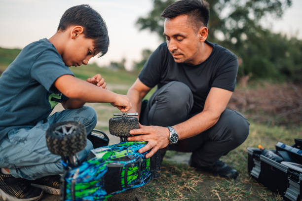 istock Father is teaching a son how to fix broken car on a remote control car 1950511497