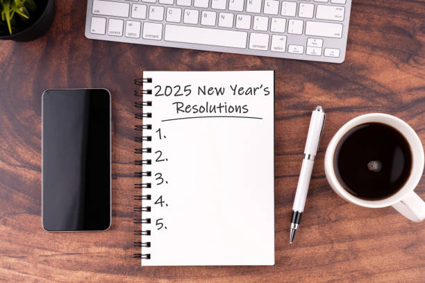 New Year's Resolutions 2025 text on note pad stock photo on wood desk