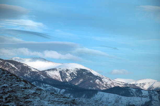 Cold snowy mountain landscape at sunset. Panoramic view of snowy mountain peaks and slopes of North Chuyskiy ridge at sunset. Russia, Siberia, Altai mountains.