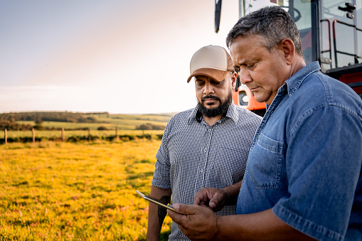 Agronomist and farmer in the field with tablet