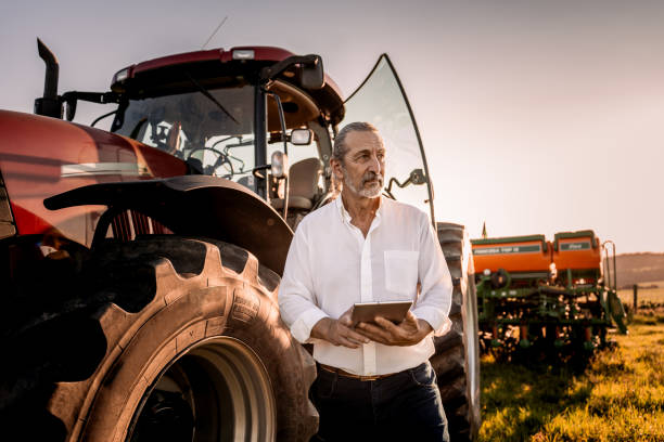 istock Farmer using tablet in the field next to the agricultural machine 1950530482