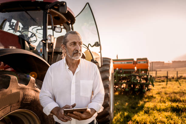 istock Farmer using tablet in the field next to the agricultural machine 1950530487