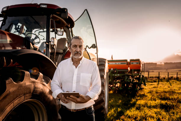 istock Farmer using tablet in the field next to the agricultural machine 1950530492
