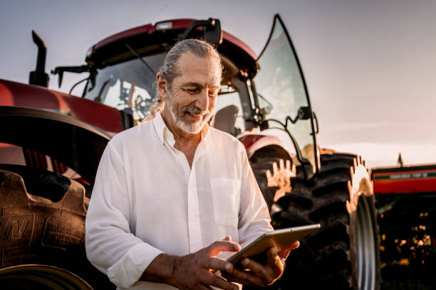 istock Farmer using tablet in the field next to the agricultural machine 1950530497