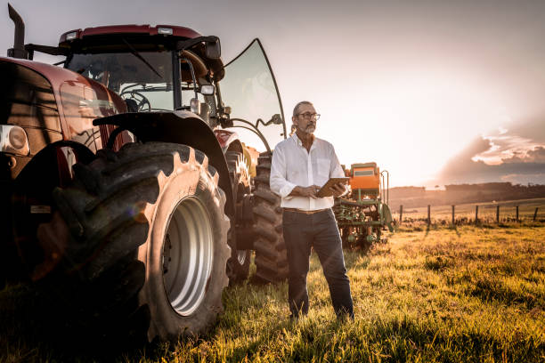 istock Farmer using tablet in the field next to the agricultural machine 1950530498
