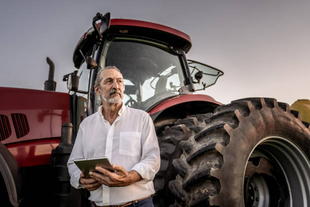 istock Farmer using tablet in the field next to the agricultural machine 1950531011