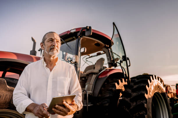 istock Farmer using tablet in the field next to the agricultural machine 1950532082
