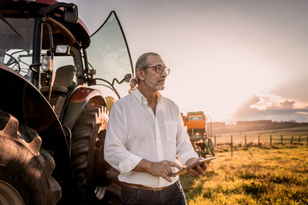 istock Farmer using tablet in the field next to the agricultural machine 1950532083
