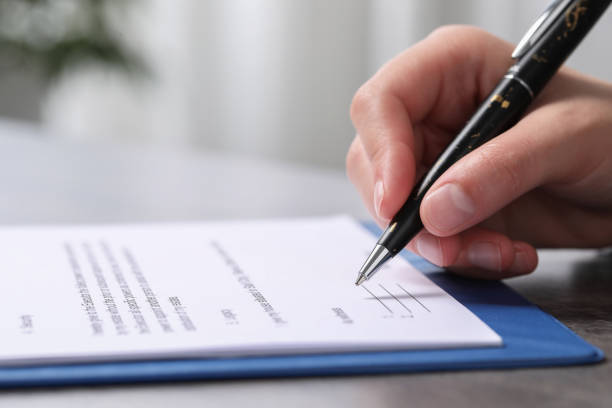 istock Woman signing document at dark table indoors, closeup. Space for text 1950572190