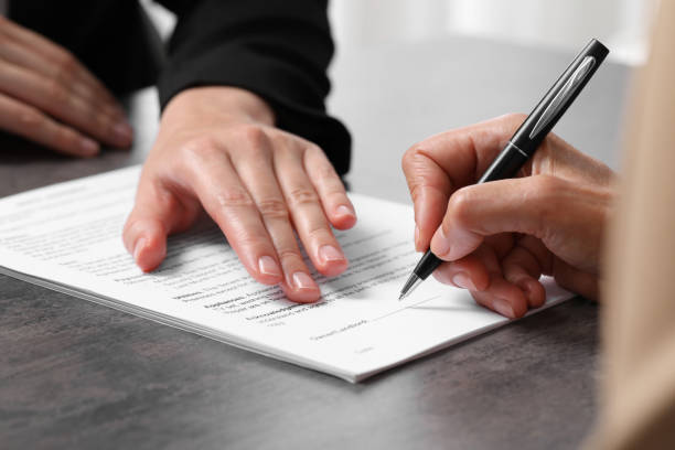 istock Manager showing client where she must to mark signature at dark table, closeup 1950572192
