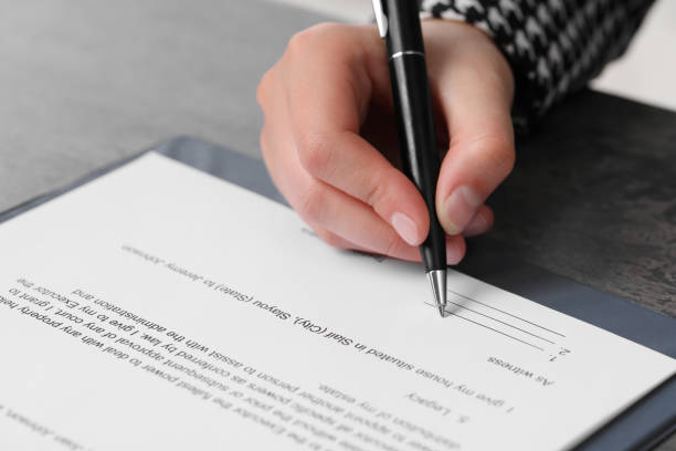 istock Woman signing document at dark table, closeup 1950572195
