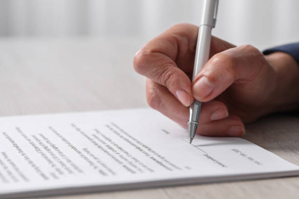 istock Woman signing document at light wooden table indoors, closeup. Space for text 1950572723