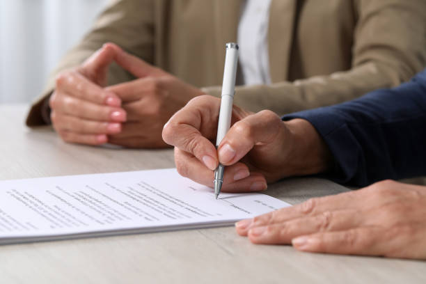 istock Signing document. Women at light wooden table indoors, closeup 1950573247