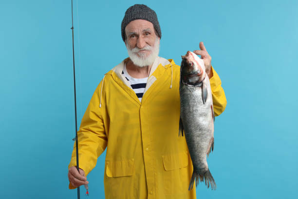 istock Fisherman with rod and catch on light blue background 1950575361
