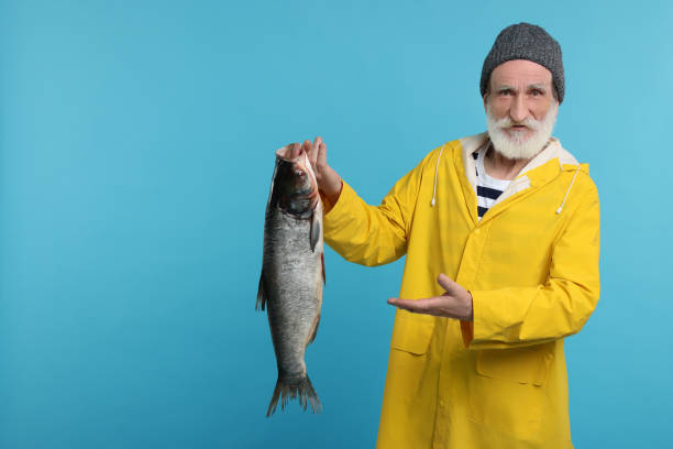 istock Fisherman with caught fish on light blue background, space for text 1950575388
