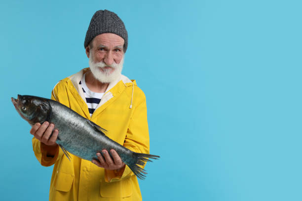 istock Fisherman with caught fish on light blue background, space for text 1950575414