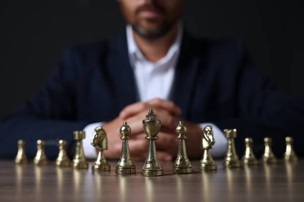 istock Man with chess pieces at wooden table against dark background, closeup 1950599452