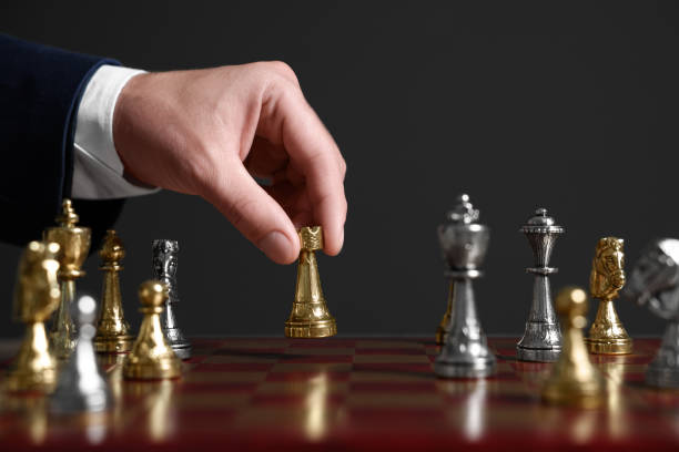 istock Man with rook game piece playing chess at board against dark background, closeup 1950602586