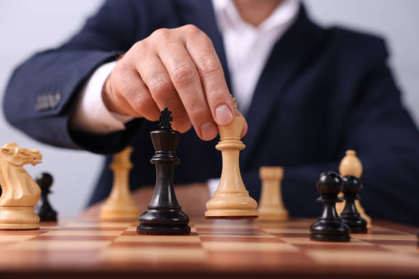 チェッカーボードでチェスをしている王のゲームピース�を持つ男、接写 - chess king chess chess piece black ストックフォトと画像