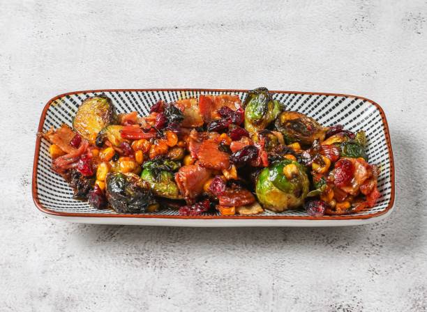 rosenkohlsalat mit tomaten und mais, serviert in einem gericht, das isoliert auf grauem hintergrund steht draufsicht auf das essen in singapur - brusselsprouts stock-fotos und bilder