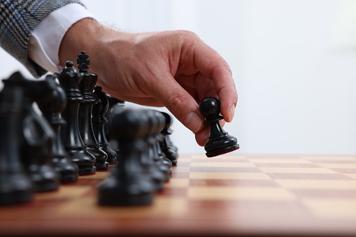 Man moving chess piece at checkerboard, closeup
