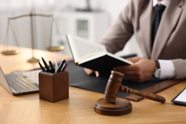 istock Lawyer reading book at table in office, focus on gavel 1950624194