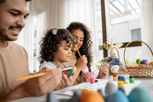 Family with daughter painting Easter eggs