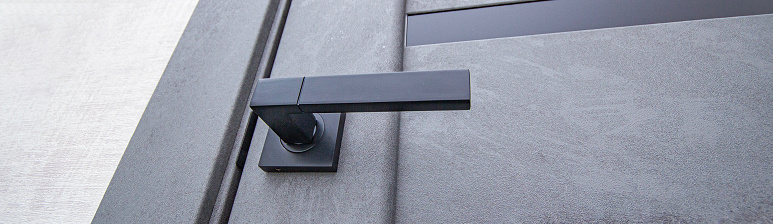 black handle on a gray ajar door close-up