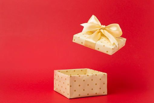 Beige open gift box on color background