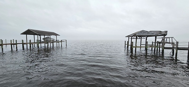 View of the Saint Johns River in Jacksonville, FL with two piers. Morning sky is overcast and gray.