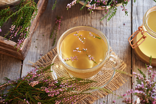 Fresh heather flowers harvested in the forest in a cup of herbal tea on a table