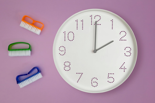 2 o'clock, afternoon. Cleaning time. White wall clock on background of kitchen brush. Time on clock is 2 pm. Cleaning service and spring organizing concept. Daytime.