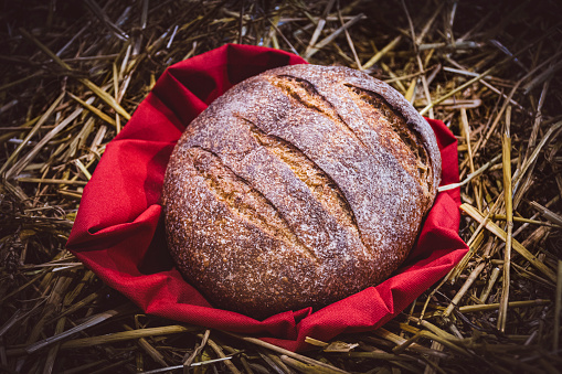 Loaf of homemade bread on hay.