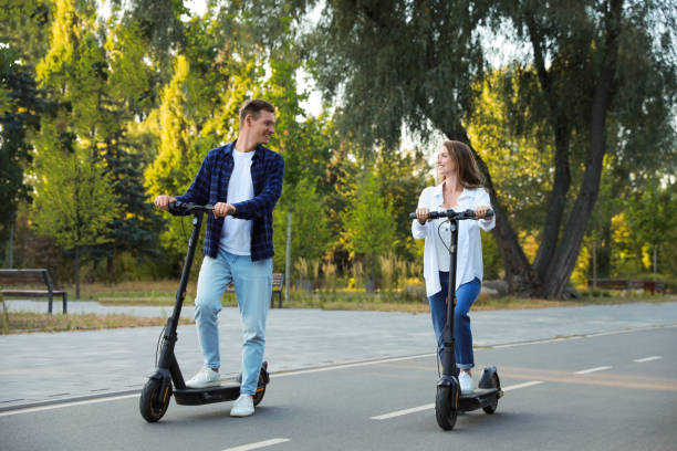 istock Happy couple riding modern electric kick scooters in park 1950759717