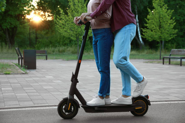 istock Couple riding modern electric kick scooter in park, closeup 1950785207