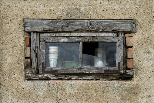 Window with a frame covered with old weathered paint, on a stone wall, framed in red brick. From the windows of the world series.
