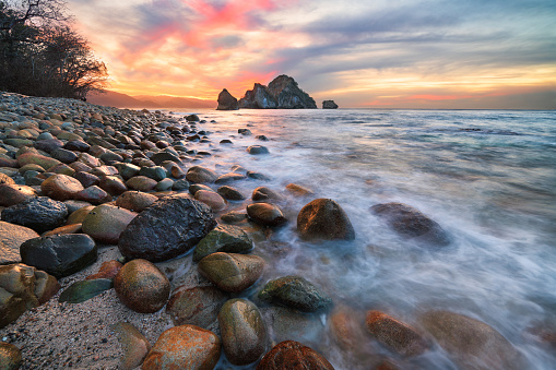 A Beautiful Ocean Sunset With Wide Angle View Of Sea Rocks And A Wave Breaking On Shore