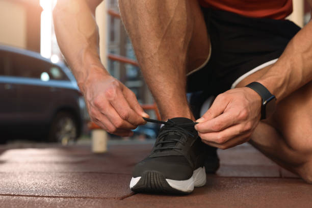 istock Man tying shoelaces before training at outdoor gym, closeup 1950839385