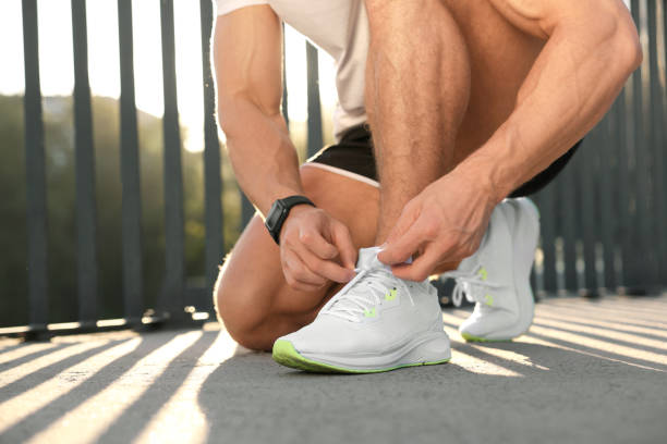 istock Man tying shoelaces before running outdoors on sunny day, closeup. Space for text 1950843768