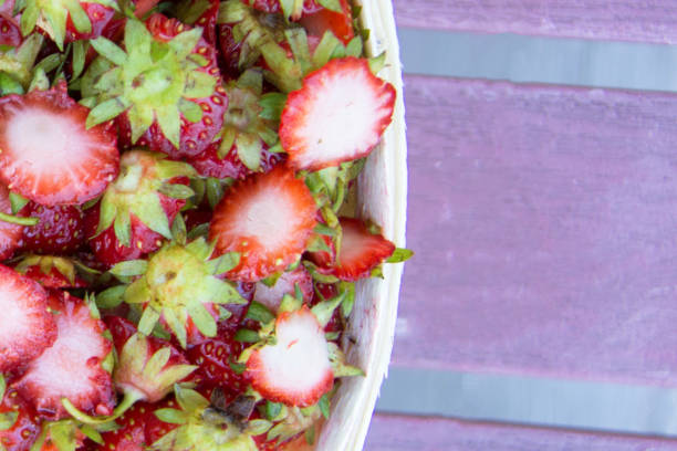 Waste of strawberries in a basket posing on wood